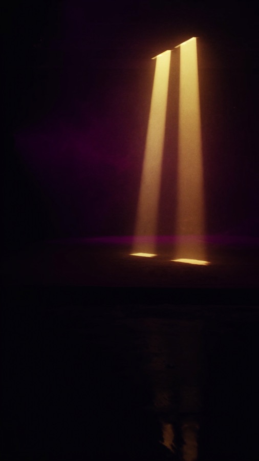 Ein senkrechter Lichtkegel auf einer dunklen Bühne, Hochformat